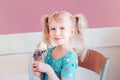 Caucasian blonde preschool girl child with blue eyes and pigtails eating holding large waffle cone with ice cream and sprinkles Royalty Free Stock Photo