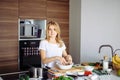 Caucasian blonde woman cooking marinade for tasty kebabs at kitchen table