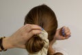 Caucasian blonde woman making a bun on a bottom of her head.