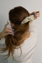 Caucasian blonde woman making a ponytail with a white scrunchy.