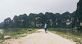 Caucasian blonde woman running towards limestone mountains in Ninh Binh province, Vietnam