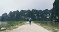 Caucasian blonde woman walking towards limestone mountains in Ninh Binh province, Vietnam