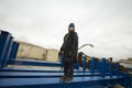 caucasian boy in a coat and hat with a scarf and walks through pipes in an industrial area Royalty Free Stock Photo