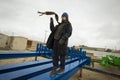 caucasian boy in a coat and hat with a scarf and walks through pipes in an industrial area Royalty Free Stock Photo