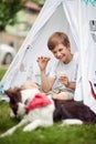 Caucasian boy eating cookie, smiling, holding glass of milk, looking at his dog Royalty Free Stock Photo