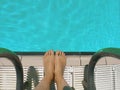 Caucasian boy feet and stairs ladders next to the swimming pool water. Top view and empty copy space Royalty Free Stock Photo