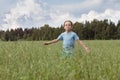 Caucasian boy on the field with a oats is running with his arms outstretched. Royalty Free Stock Photo