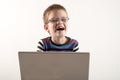 A Caucasian boy with glasses tries to work with a computer and the Internet. The guy gets vivid emotions