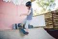 Caucasian boy in a helmet does tricks on a skateboard on a playground for skateboarding outside. A child skateboarder rides a