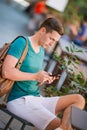 Caucasian boy is holding cellphone outdoors on the street. Man using mobile smartphone. Royalty Free Stock Photo
