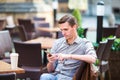 Caucasian boy is holding cellphone outdoors on the street. Man using mobile smartphone. Royalty Free Stock Photo