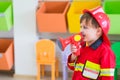 Caucasian boy kid dress up to fireman and use speaker at roll play classroom,Kindergarten preschool education concept Royalty Free Stock Photo