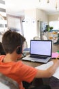 Caucasian boy learning and using laptop with copy space and headphone