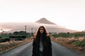 caucasian boy with long disheveled hair and a coat looking at camera calm and relaxed standing on the wet road leading Royalty Free Stock Photo