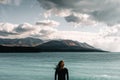 caucasian boy with long loose disheveled hair standing calm looking at the sea and mountains wearing a black t-shirt Royalty Free Stock Photo