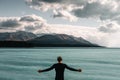 caucasian boy with long messy bun hair standing on his back with open arms and a black t-shirt looking at the wild sea Royalty Free Stock Photo