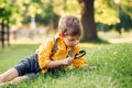 Caucasian boy looking at plants grass flowers in park through magnifying glass.