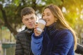 Caucasian boy looking at a smiling latina girl drinking coffee on the bench in a public park Royalty Free Stock Photo