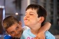 Caucasian boy with mouth full of food laughing with his brother. Hungry child eating big chocolate piece of cake in a modern