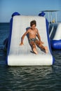 Caucasian boy of nine year old having fun at the inflatable beach aqua slide Royalty Free Stock Photo