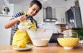 Caucasian boy pouring milk into a bowl and preparing the ingredients to make a cake