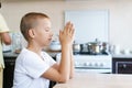 Caucasian boy prays at home at the table before eating. Stay home and pray Royalty Free Stock Photo