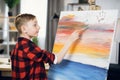 Caucasian boy using brush for painting on easel at sudio
