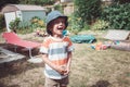 Caucasian boy wearing stripped tshirt and hat with funny face expression outside on house backyard on summer day, crying