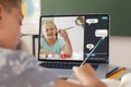 Caucasian boy writing homework while studying online with girl over video call on laptop at home Royalty Free Stock Photo