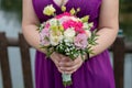 Caucasian bridesmaid wearing a beautiful purple gown and holding a bridal round bouquet Royalty Free Stock Photo