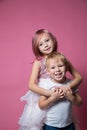 Caucasian brother and sister ,hugging on camera on pink background studio shot.