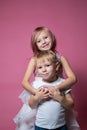 Caucasian brother and sister ,hugging on camera on pink background studio shot.