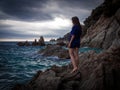 Caucasian brunette girl standing on the rocks near the rippling sea Royalty Free Stock Photo