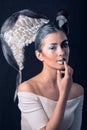 Caucasian Brunette with Half Face Painted with White and Half Graphic Black Make-up, Touching her Lip, on Black Background. Angel Royalty Free Stock Photo