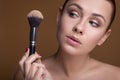 Caucasian brunette woman apply blush on a cheekbone with a brush. Close up portarait. Skin care  concept Royalty Free Stock Photo