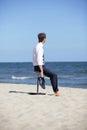 Caucasian business man sitting on pneumatic stool on the beach