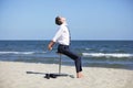 Caucasian business man stretching body on pneumatic stool on the beach