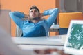 Caucasian business person sitting in office thinking daydreaming hands behind head.