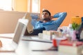 Caucasian business person sitting in office thinking daydreaming hands behind head. Royalty Free Stock Photo