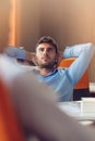 Caucasian business person sitting in office thinking daydreaming hands behind head. Royalty Free Stock Photo