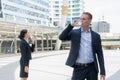 Caucasian businessman and Asian business woman standing and drinking pure mineral water from plastic bottle. Royalty Free Stock Photo