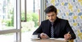 Caucasian businessman in black suit taking a note while reading text message on mobile phone during lunch break. Atmosphere in a Royalty Free Stock Photo