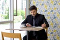 Caucasian businessman in black suit taking a note while reading text message on mobile phone during lunch break. Atmosphere in a Royalty Free Stock Photo