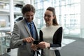 Caucasian businessman and Caucasian businesswoman discussing over mobile phone near escalator Royalty Free Stock Photo