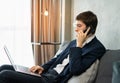 caucasian businessman calling by mobile phone, working with laptop, wear suit, sitting, looking at computer. Young man work Royalty Free Stock Photo