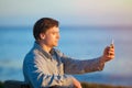 Caucasian businessman holding cellphone overlooking ocean at sun Royalty Free Stock Photo