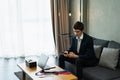 caucasian businessman working with mobile phone, wear suit, sit on sofa, working with laptop and note on desk. Young man work Royalty Free Stock Photo