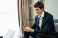 caucasian businessman working with mobile phone, wear suit, sit on sofa, working with laptop. Young man work business with home Royalty Free Stock Photo