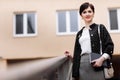 Caucasian businesswoman holding paper notebook, walking by office building. Beautiful smiling female in stylish office Royalty Free Stock Photo