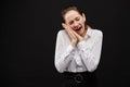 Caucasian businesswoman in a white shirt on a black background. A gesture depicting fatigue, drowsiness, desire to sleep